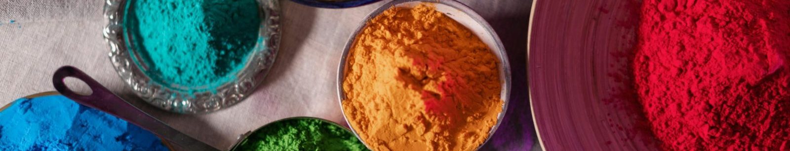 Colorful Holi festival powders in various bowls on a flat surface from above.